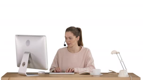 Όμορφη νεαρή περιστασιακή γυναίκα φορώντας ακουστικά που εργάζονται σε υπολογιστή σε λευκό φόντο. — Αρχείο Βίντεο
