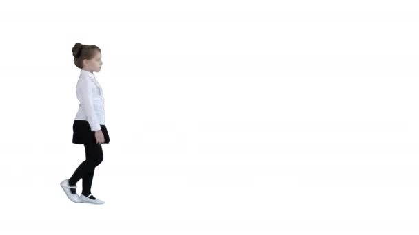 Holčička ve školní uniformě chůze na bílém pozadí. — Stock video