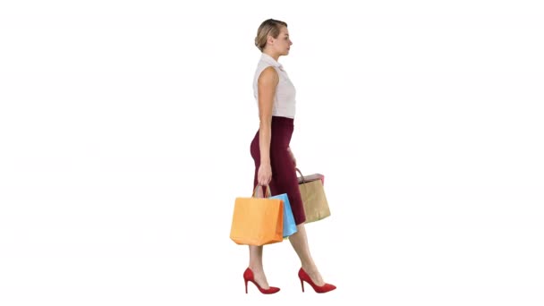 Heureuse femme pleine longueur tenant des sacs à provisions en papier dans chaque main et marchant sur fond blanc . — Video