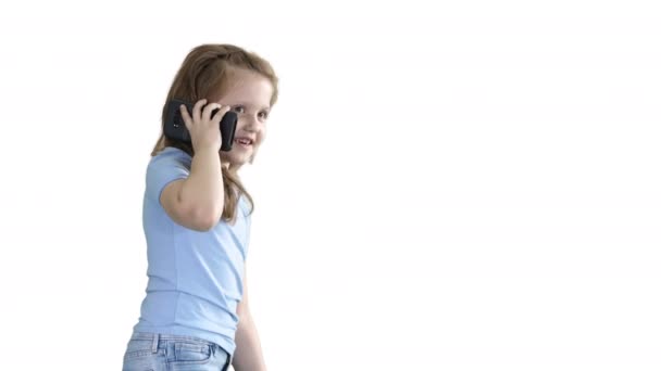 Klein meisje praat telefoon en wandelen op witte achtergrond. — Stockvideo