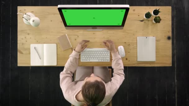 Žena, která dělá video, sedí u stolu s počítačem. Obrazovka se zelenou obrazovkou. — Stock video