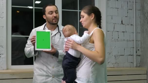 Läkare som visar mamma och hennes unge medicinska resultat på tabletten. Grön skärm mock-up display. — Stockvideo