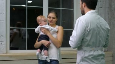 Doktor elinde bir çocuk ile anne konuşuyor.