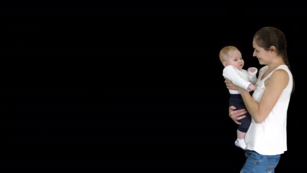 Jonge moeder houdt haar baby in handen en loopt, Alpha Channel — Stockvideo