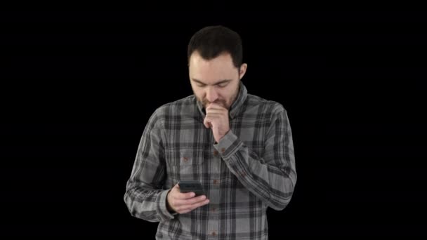 Грустный молодой человек идет и смотрит на свой мобильный телефон с рукой на лице, Альфа-канал — стоковое видео