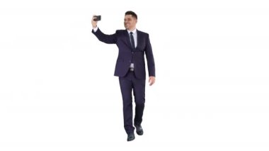 Takım elbiseli yakışıklı adam beyaz arka planda yürürken selfie çekiyor..