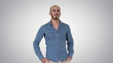 Yakışıklı genç Arap adam rahat bir kıyafet yürüyüş giyen, degrade arka planda ceplerinde iki elini koyarak.