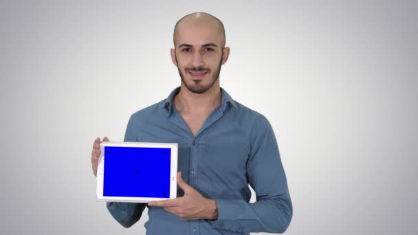Smiling casual man presenting a tablet with a blank screen on gradient background. — Stock Video