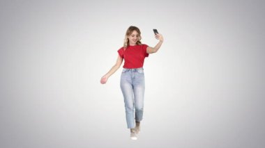 Neşeli genç hippi kız gradyan arka planda yürürken internet günlüğü için video yayınlıyor.