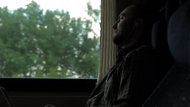 Muž se sluchátky ve vlaku se dívá do okna. — Stock video