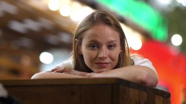 Samotna słodka dziewczyna leżąca na stole i patrząca na ciebie uśmiechnięta. — Wideo stockowe
