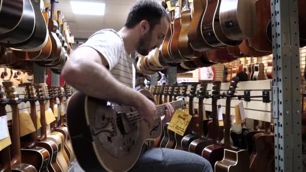 Μόντρεαλ, Κεμπέκ, Καναδάς - 25 Ιουνίου, 2018: Άνθρωπος που δοκιμάζει κιθάρα σε κατάστημα κιθάρας. — Αρχείο Βίντεο