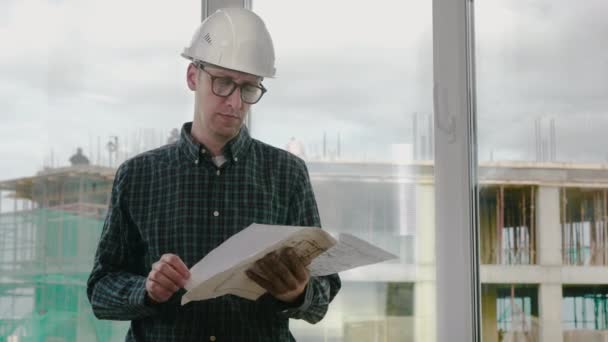 Construction engineer looking at blueprint and the room in front of him. — Stock Video
