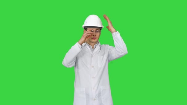 Scienziato Ingegnere in vestaglia bianca, casco di sicurezza e occhiali Fare mosse divertenti con gli occhi alla fine su uno schermo verde, Chroma Key. — Video Stock