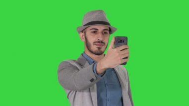 Gündelik kıyafetler içinde Arap adam yürüyüş ve Yeşil Ekranda selfie yapma, Chroma Key.