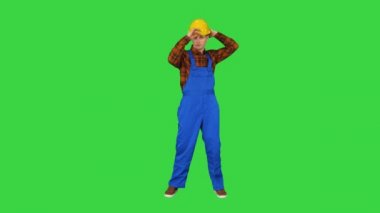 Bekar inşaat işçisi güvenlik şapkası takar ve yeşil ekranda dans eder, Chroma Key.