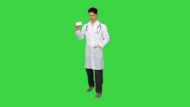 Tıp doktoru elinde bir kutu hap tutuyor ve yeşil ekranda dans ediyor, Chroma Key..