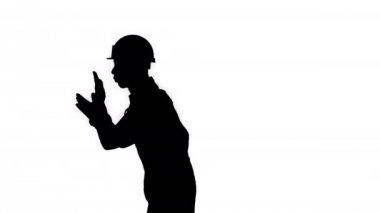 Siluet İnşaat işçisi çalışmaya istekli, çalışmaya hazır. O elleri alkışlar ve serin flip yapar sonra kameraya gülümsüyor.