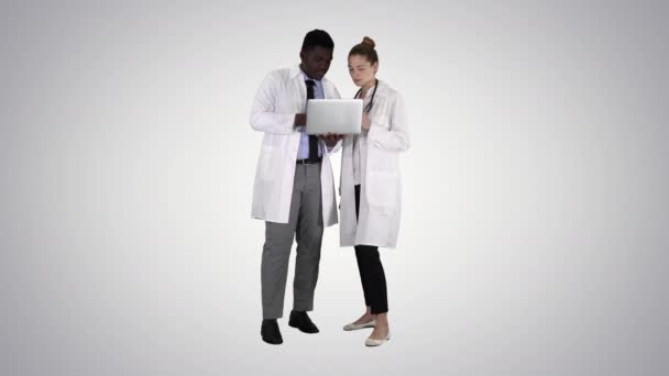 Medical staff working in front of a grey laptop while standing on gradient background. — Stock Video