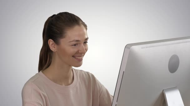 Student blonde girl looking at monitor of computer and smiling on gradient background. — Stock Video