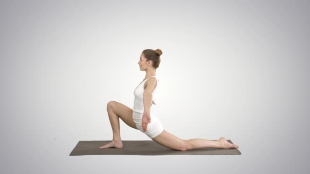 Sportif çekici kız yoga, At binici egzersiz ayakta, anjaneyasana gradyan arka plan üzerinde poz. — Stok video