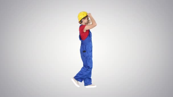 Young attractive woman in construction uniform putting on yellow helmet on gradient background. — Stock Video