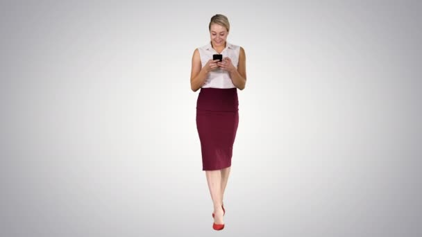 Donna datore di lavoro di successo digitando un messaggio di testo sul suo cellulare mentre cammina su sfondo sfumato. — Video Stock