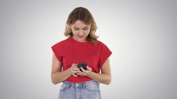Degrade arka planda akıllı telefonunu kullanarak t shirt genç güzel kadın. — Stok video