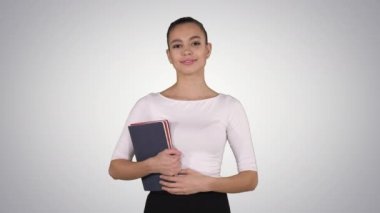 Not defterleri olan genç ve güzel bir kadın, arka planda yürüyor..