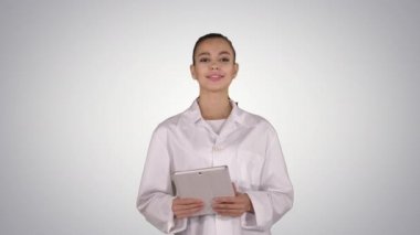 Mutlu kadın doktor tablet bilgisayar kullanarak gradyan arkaplan sayfalarını karıştırıyor.