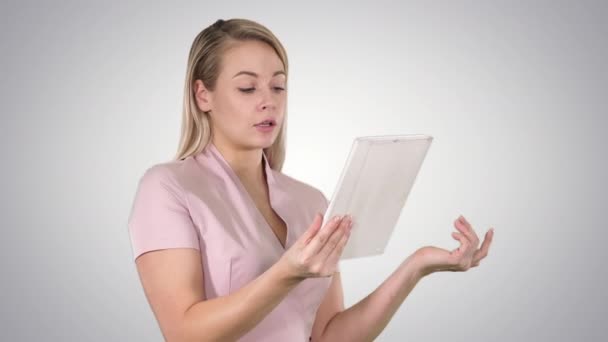Femme heureuse bavarder sur un appel vidéo, en utilisant une tablette sur fond de dégradé . — Video