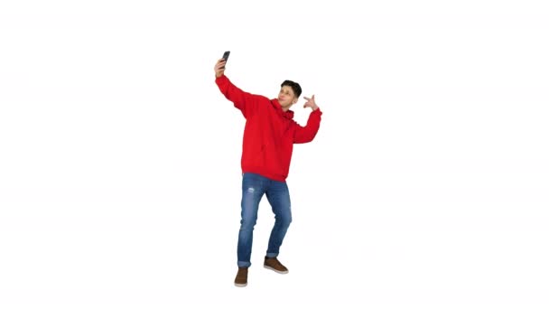 興奮したカジュアルな男が踊り、白い背景に自分の携帯電話で自分撮りを作ります. — ストック動画