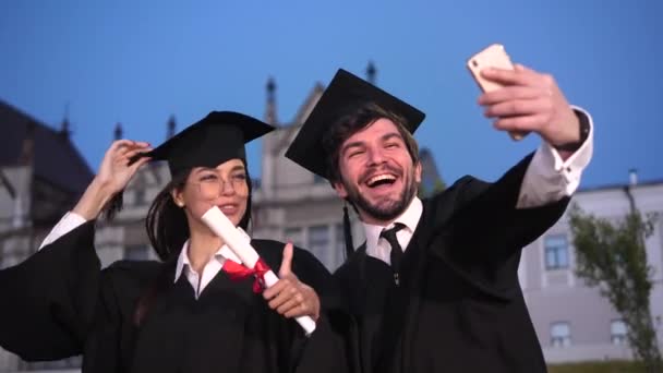 Estudiantes de posgrado de sexo masculino y femenino tomando una selfie con teléfono móvil. Pareja emocional. — Vídeo de stock
