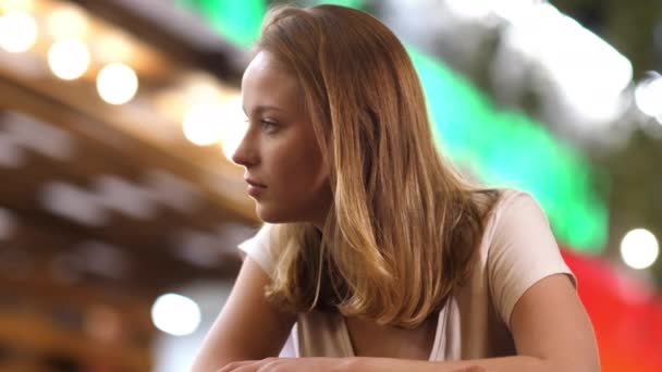 Chica rubia escuchando a alguien sentado en un café al aire libre . — Vídeos de Stock