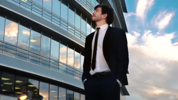 Молодий бізнесмен, дивлячись вгору з посмішкою день мріє стояти перед діловим центром . — стокове відео