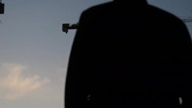 Mühendis ya da mimar kişisel koruyucu ekipman takıyor. Güvenlik kaskı gün batımında binayı kontrol ediyor..