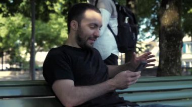 Adam parkta akıllı telefon kullanıyor. Telefonuna kimse gözetlemez..