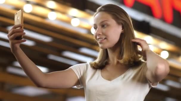 Mooie vrouw borstelen haar haar met behulp van een smartphone als spiegel. — Stockvideo