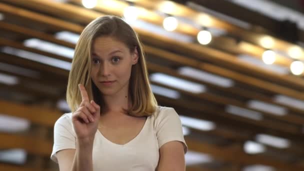 Tengo una idea. Joven mujer de pelo rubio bonita de pie y apuntando con el dedo índice hacia arriba . — Vídeos de Stock