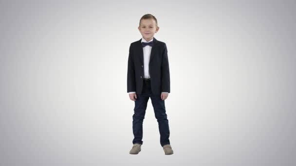 Mosolygó kisfiú formális ruhában állva gradiens háttér.