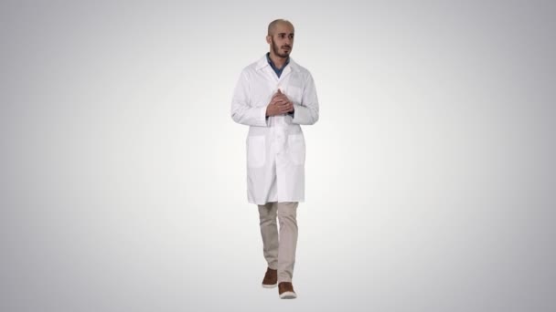 Arzt mittleren Alters in medizinischer Uniform präsentiert und zeigt mit der Handfläche in die Kamera auf dem Hintergrund des Gefälles. — Stockvideo