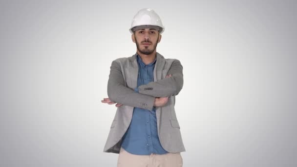 自信を持って建設技師の建築家はヘルメットで、手はグラデーションの背景に折り畳まれる. — ストック動画