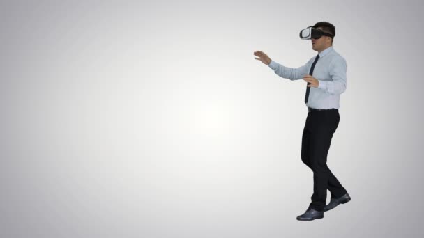 Businessman in virtual reality headset walking in virtual world on gradient background. — Stock Video