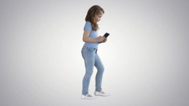 Küçük kız degrade arka planda yürürken akıllı telefon ile oynuyor.
