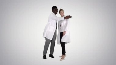 İki doktor akıllı telefon kullanarak özçekim yapıyor ve gradyan arka planda gülümsüyor..