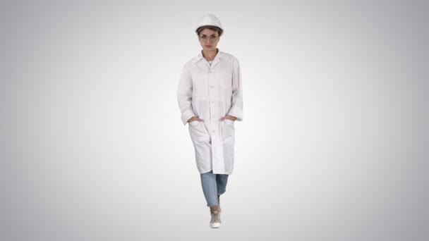 Mujer en una bata de laboratorio de gradiente y sombrero duro caminando sobre fondo de gradiente . — Vídeos de Stock