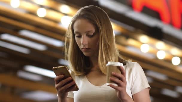 Belle femme debout avec une tasse de café, textos au téléphone. — Video