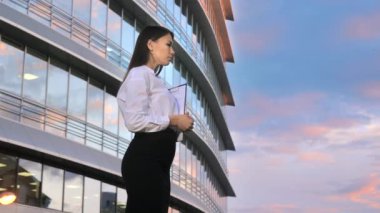 Gülümseyen kadın ayakta ve dışarıda birini bekliyor.