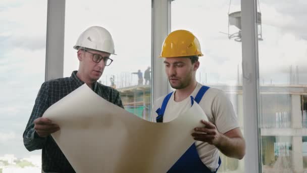 Ingeniero y trabajador de la construcción discuten un plan . — Vídeo de stock