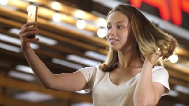Söt tonåring flicka med mobiltelefon som spegel för att fixa hår. — Stockvideo